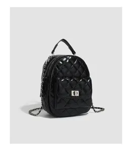 Detail view of a black quilted mini backpack featuring chain straps and metallic twist-lock.