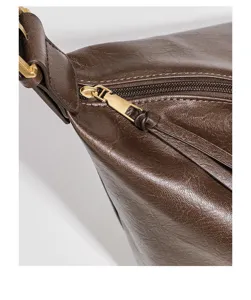Detailed view of the dark brown leather shoulder bag, showcasing premium texture and gold hardware.