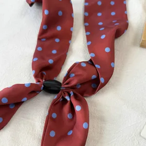 Close-up of the red polka dot silk scarf featuring a sleek black magnetic buckle accessory.