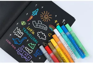 Detalle de rotuladores acrílicos de colores con tinta brillante sobre cuaderno negro.