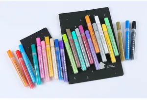 Primer plano de marcadores acrílicos coloridos ordenados sobre cuadernos negros.