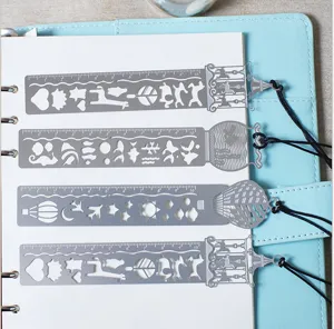 Metal hollow-out drawing template ruler bookmark set of 4 pieces displayed on a notebook.