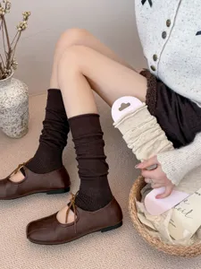 Detail view of ballet-style slouch leg warmers and brown shoes, cozy autumn aesthetic style.