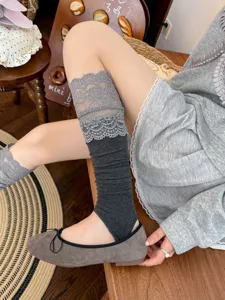 Close-up detail of grey lace stirrup leg warmers, sweet Lolita style knit stack socks.