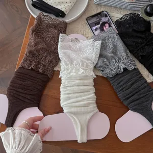 Detail shot of sweet Lolita lace stirrup leg warmers in various colors on wooden table.