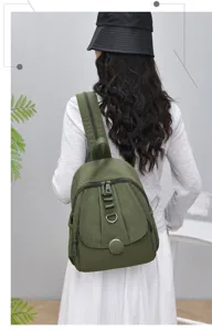 Backpack detail view showcasing olive green fabric, multi-zipper pockets, and adjustable straps.