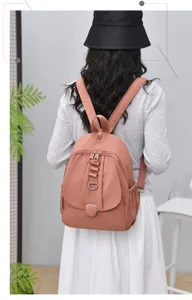 Detail view of a stylish pink women's backpack, featuring multi-pocket design and metallic rings.