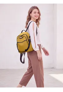Detailed close-up shot of the fashionable yellow travel backpack worn by a model in a scene.