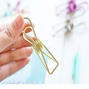 Detalle de sujetapapeles metalico dorado, diseno minimalista para organizar documentos.