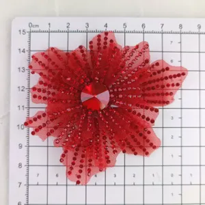 Gros plan détaillé d'accessoire DIY de fleur en strass et résille rouge scintillante.