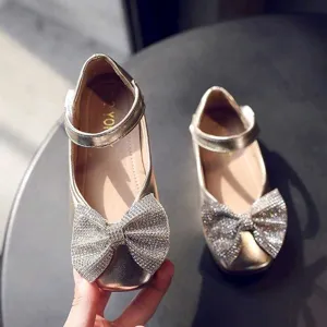 Detailed view of sparkly rhinestone bow on gold girls shoes, close-up shoe decoration.