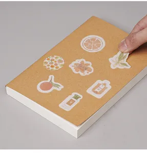 Vintage notitieboek detail met creatieve fruit- en plantenstickers die worden afgepeld.