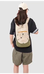 Outdoor folding backpack detail view, featuring beige and green nylon fabric with bungee cord.