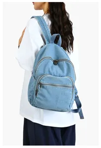 Vue détaillée du sac à dos en denim décontracté montrant le port et la texture du tissu.