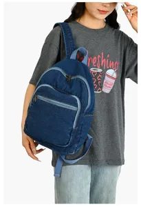 Vue détaillée du sac à dos en jean bleu avec poche zippée avant et bretelles solides.