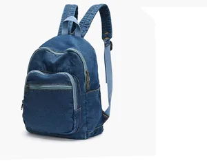 Détail du sac à dos en jean bleu avec un tissu résistant et une poche zippée pratique.