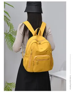 Detailed view of women's yellow nylon casual backpack with multiple zippers and durable straps.