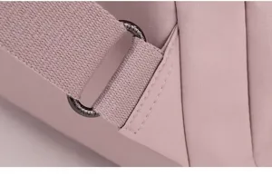 Detailed view of pink nylon backpack strap and metal hardware adjuster, durable travel bag.