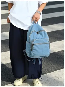 Détail de sac à dos en denim décontracté avec tissu lavé bleu clair et poches zippées.