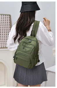 Detailed view of the army green nylon backpack, highlighting multiple zipper pockets.