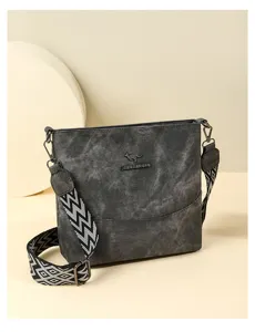 Detailed view of the dark grey soft leather bucket bag with wide chevron patterned strap.
