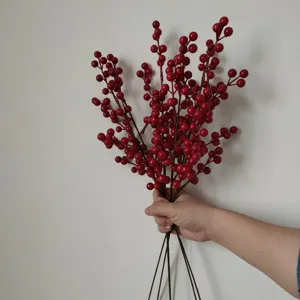Detail view of artificial red berry branch, vibrant red fruit stems for holiday home decor.