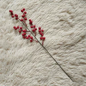 Detailed view of artificial red berry branch, vibrant holiday floral arrangement prop.