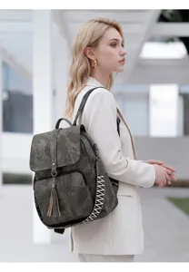Detailed view of the vintage washed fabric backpack with ethnic woven strap and tassel charm.