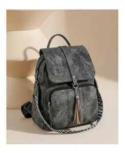 Vintage washed fabric backpack detail, featuring ethnic woven strap and chic tassel charm.