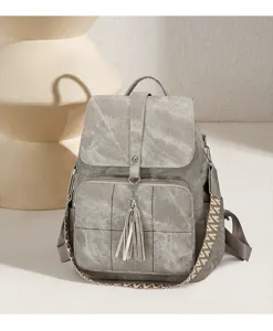 Close-up detail of vintage washed backpack with ethnic strap, tassel charm and front pocket.