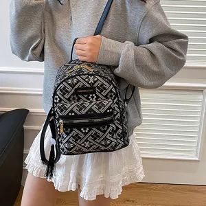 Women's mini nylon backpack with geometric embossed pattern, tassel charm and front pocket.