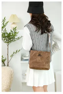 Detail shot of the brown soft leather shoulder bucket bag with wide strap and logo.