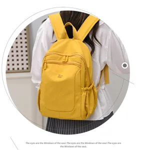 Closeup detail of a vibrant yellow nylon backpack featuring multi-zipper pockets and side pouches.