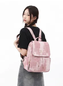 Pink washed denim pattern backpack detail showing dual straps, flap, and front pocket.