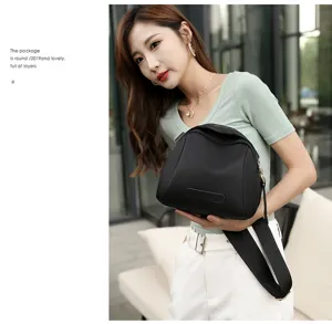 Detailed view of the black canvas crossbody bag with wide strap, fashionable shell design.