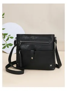 Detailed closeup view of a stylish black leather crossbody bag with tassel and zipper pockets.