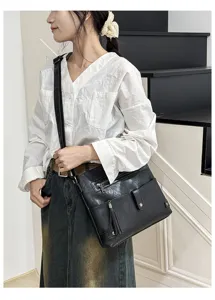Black fringe crossbody bag detail view worn by model showcasing stylish shoulder strap design.