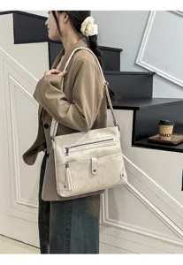 Detail view of stylish beige shoulder crossbody bag with tassel and zipper for women.