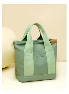 Green canvas tote bag detail view, small lunch bag with dual handles and leather tag.
