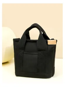 Black canvas tote bag detail view showing sturdy double handles and front pocket.