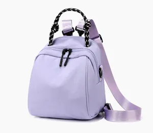 Purple mini backpack detail view showcasing dual zippers and unique black white handle texture.