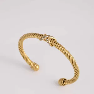 Goldfarbenes verdrehtes Kabelarmband Detail mit elegantem X-förmigen Strass-Mittelknoten.