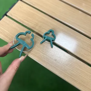 Green plant fixing clips detail view, showing size comparison and spring structure for garden.