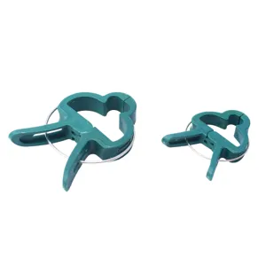 Close-up detail of green plastic plant support clips with metal springs for garden gardening.