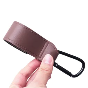 Vue détaillée de la sangle en cuir PU marron et du crochet de poussette en métal noir.