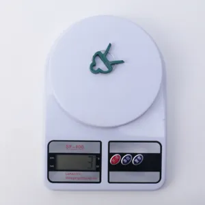 Green plant clips for garden tomato support, plastic fixing clips detail view weighing test.