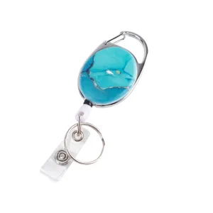 Close-up of a retractable badge reel with a turquoise pattern oval face and carabiner clip.