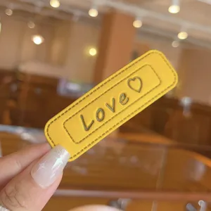 Detailed view of yellow leather square hair clip with love heart pattern for women.