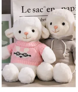 Detailed close-up view of cute plush white lamb stuffed toys wearing knit sweater and grey hoodie.