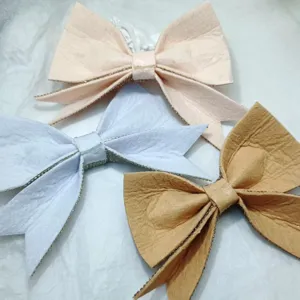 Detailed shot of DIY fabric bow shoe charms with rhinestone trim, multi-color craft accessories.